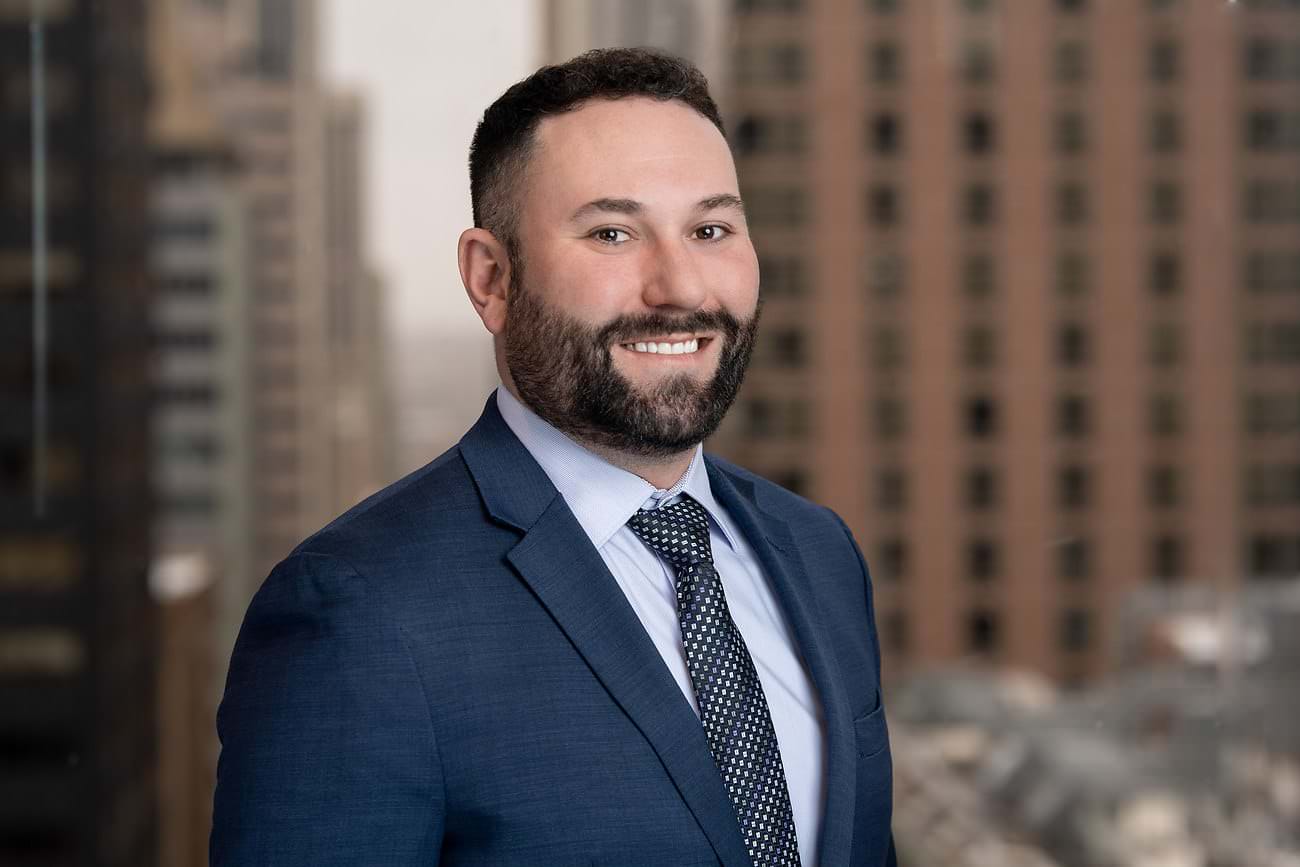 a man in a suit and tie smiling in front of a city.