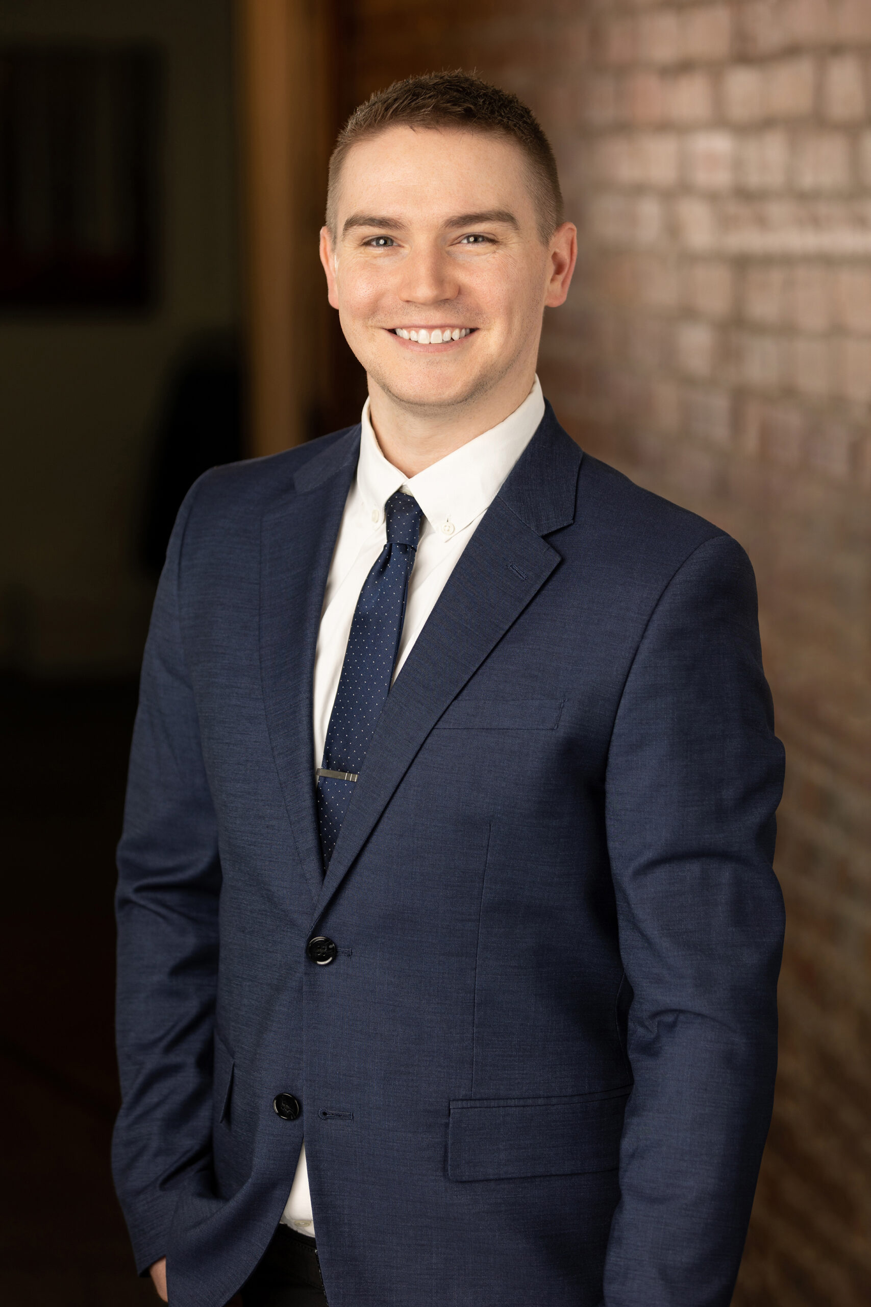 a man in a suit is smiling in front of a brick wall.