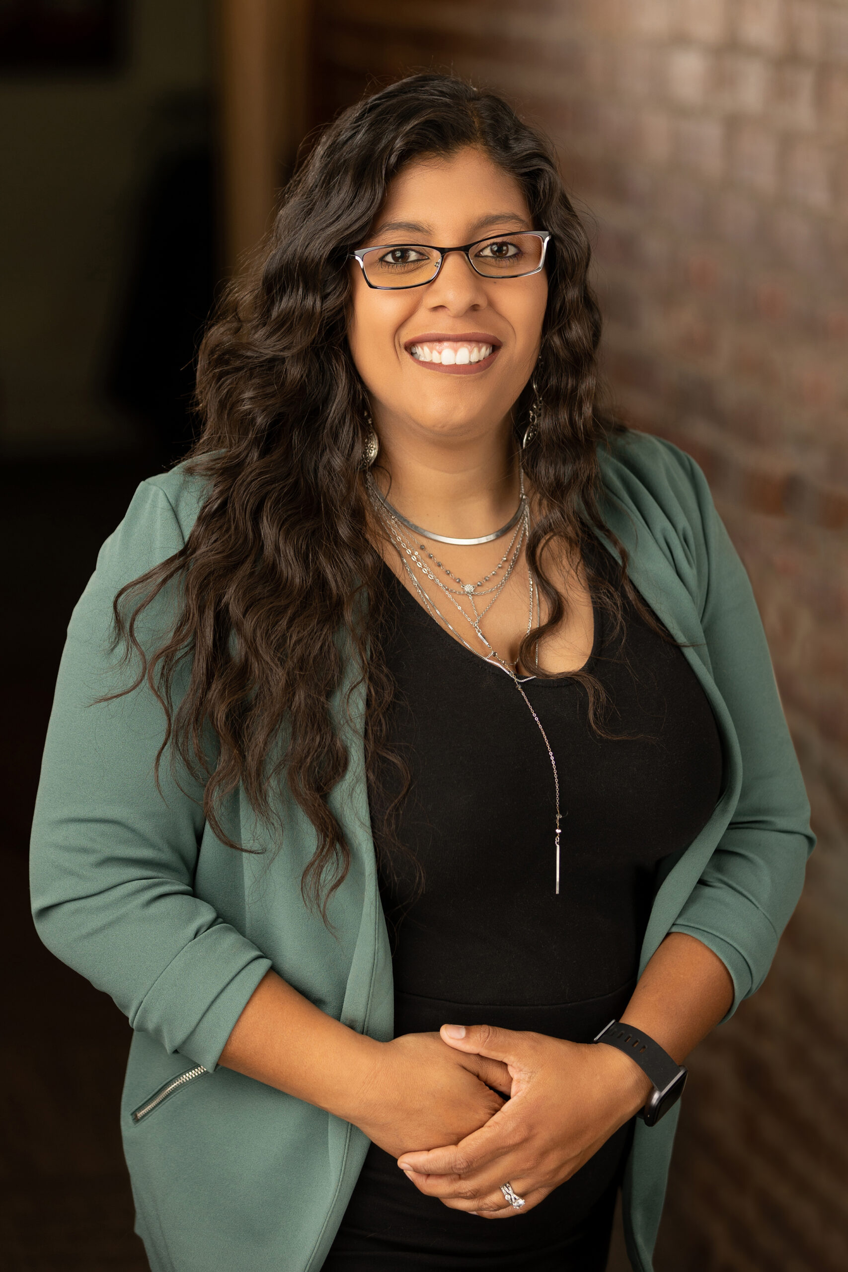 a smiling woman wearing glasses and a green blazer.