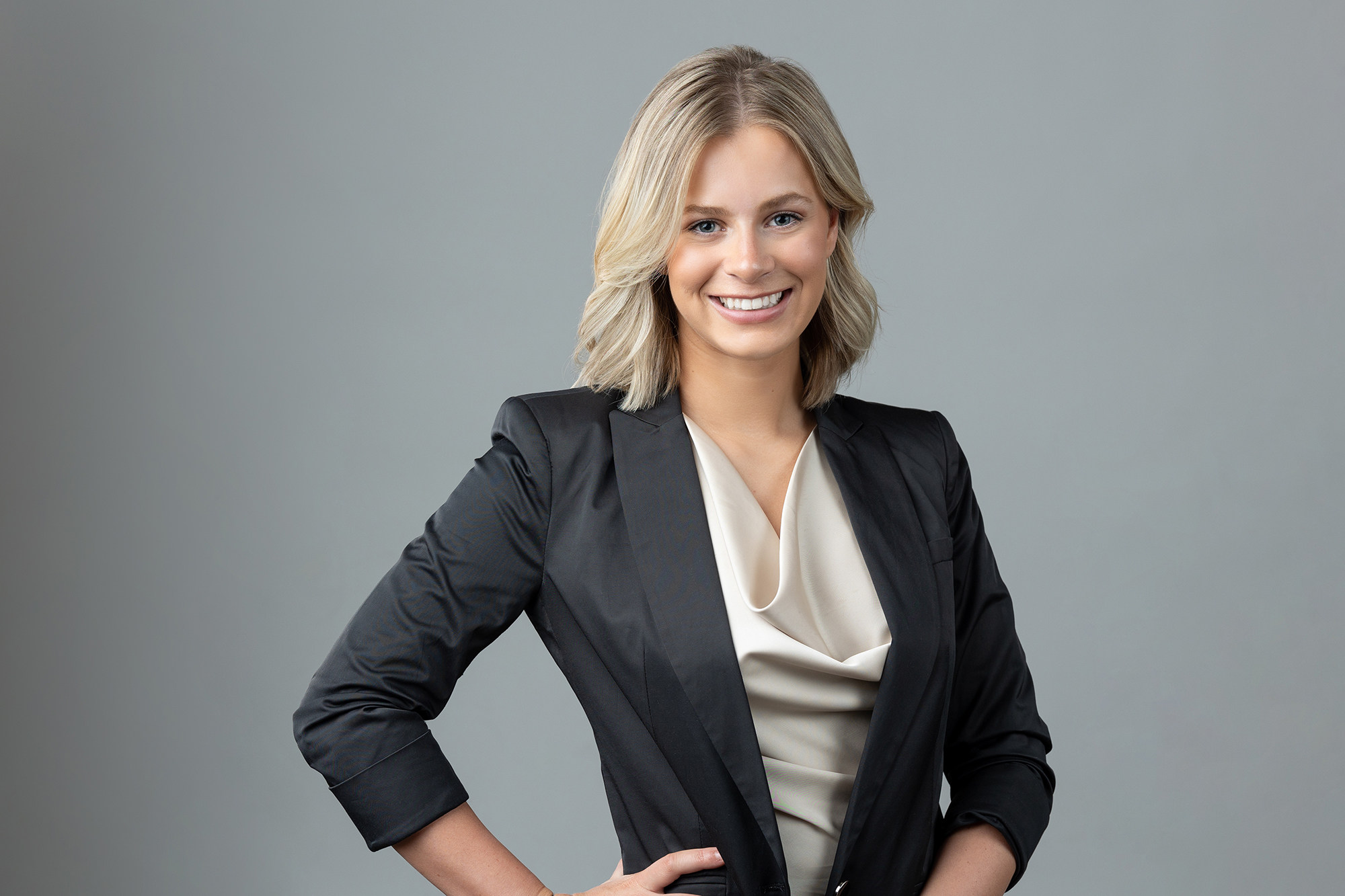 A professional business woman in a suit elegantly posing for a headshot photo.