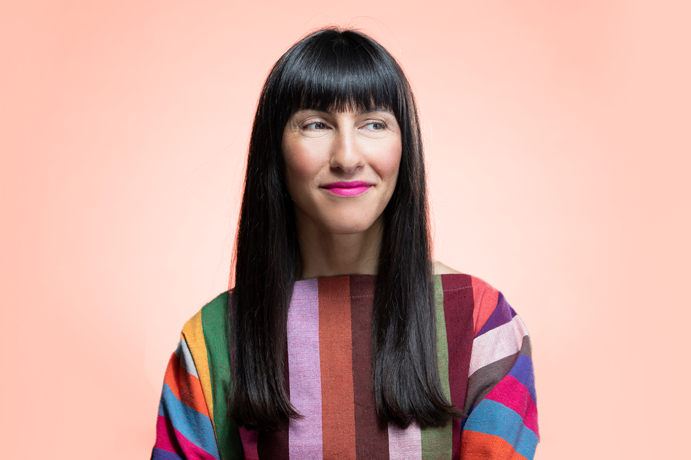 a woman with long black hair in a colorful striped top, headshot.