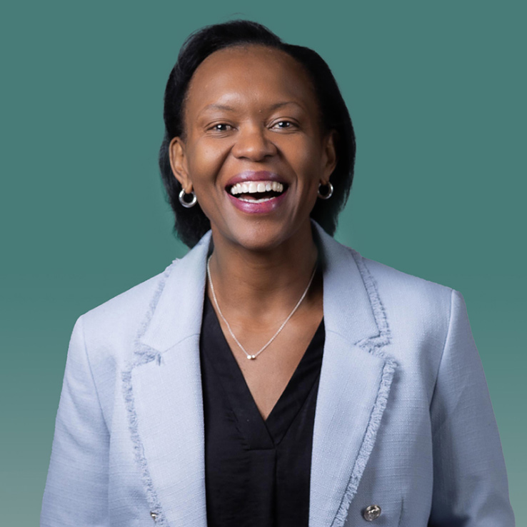 A smiling person wearing a light blue blazer and black top against a green gradient background, perfectly capturing the professional essence promoted by Denver Headshot Co.