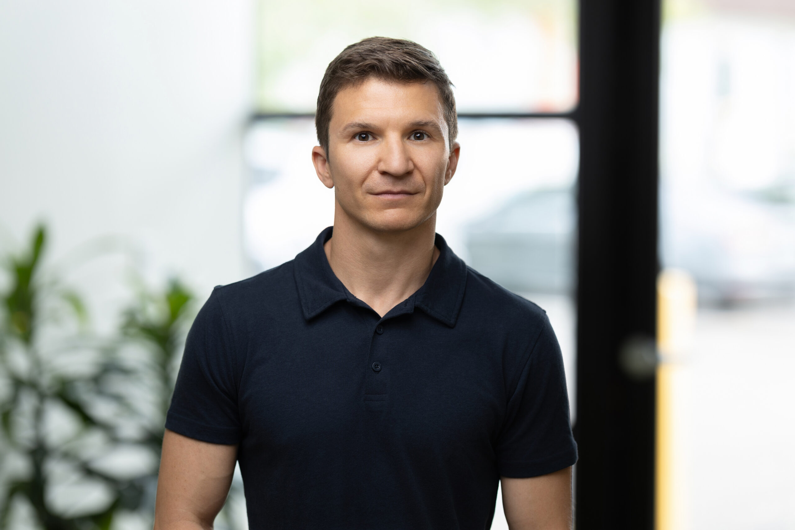 A person in a black polo shirt stands indoors with a blurred background, perfectly capturing the essence of a professional headshot for their photography portfolio.